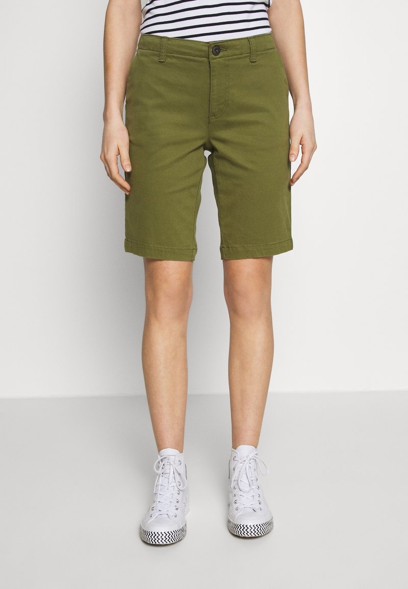 Oliivinvihreät puuvillaiset shortsit, joissa suora leikkaus, kantatut reunat ja edessä nappikiinnitys. Yhdistetty valkoisten tennarien kanssa.