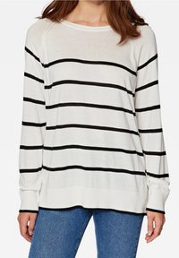 Maglione bianco a maniche lunghe con righe orizzontali nere, una vestibilità comoda e polsini a costine. Abbinato a jeans blu per un look casual.