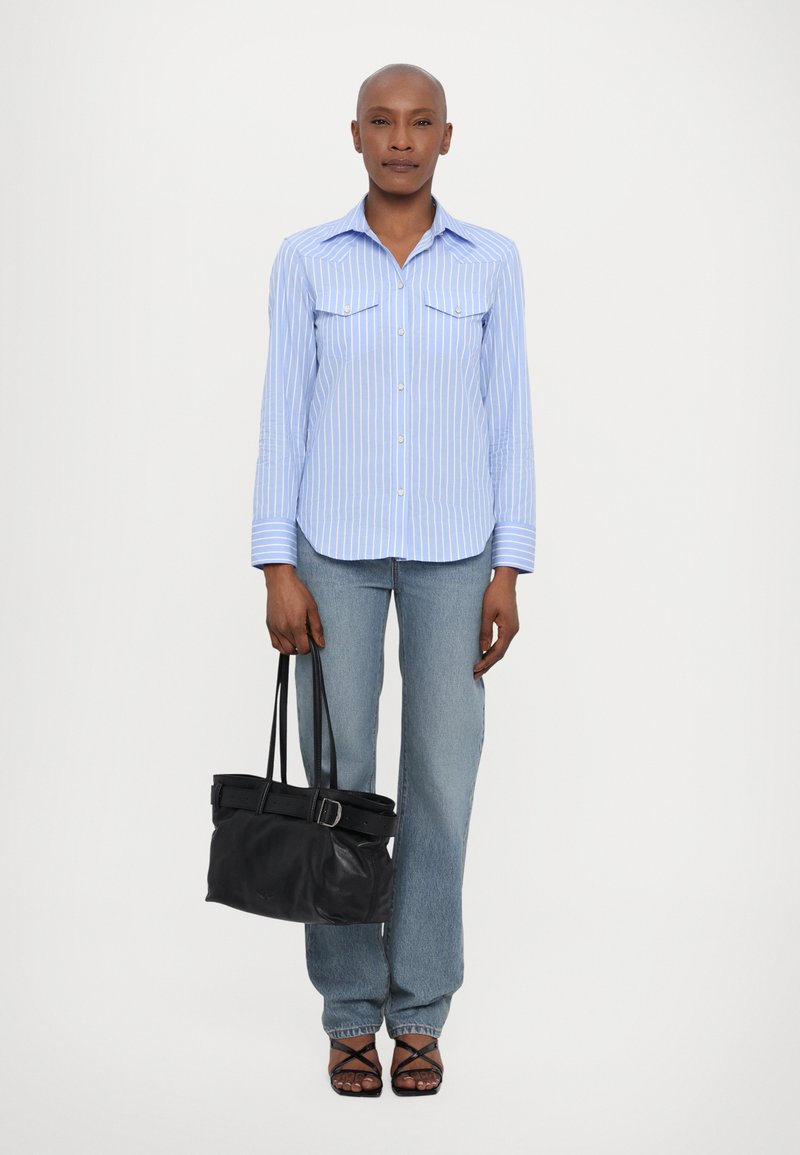 Blue and white striped button-up shirt, light denim jeans, black leather bag with belt detail, and strappy black sandals.