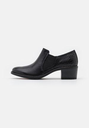 Chaussure noire à petit talon, sans lacets, avec un avant en cuir lisse, un panneau latéral élastique et un motif texturé peau de serpent sur la zone du talon.
