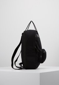 Svart ryggsäck med en elegant design, som har ett huvudfack, sidoficka och justerbara axelremmar. Tillverkad av slitstarkt material.