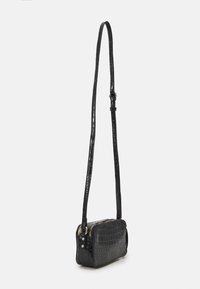 Borsa a tracolla in pelle nera con stampa a coccodrillo, dotata di una lunga tracolla regolabile e chiusura con zip. Forma rettangolare compatta con superficie liscia.