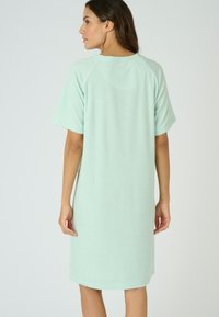 Abito verde menta a maniche corte con vestibilità rilassata e maniche raglan. Tessuto morbido e testurizzato, che arriva appena sopra al ginocchio. Design semplice, senza motivi.