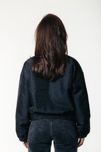 Fekete pöttyös dzseki elasztikus mandzsettákkal és derékrésszel, laza fazonú és puha tapintású, sötét, testhez simuló farmerral párosítva.