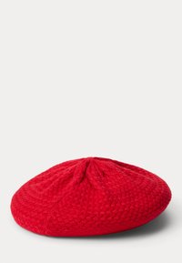 Piros kötött beret, lekerekített formával és texturált mintázattal, középen húzott varrással és sima alsó résszel.