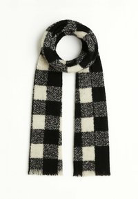 Sciarpa a scacchi bianca e nera realizzata in tessuto morbido, con estremità sfrangiate e design ad anello per avvolgerla intorno al collo.
