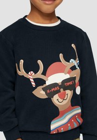 Marineblauwe sweatshirt met een cartoon rendier met hoorns, dat een zonnebril en een rode hoed draagt, en een feestelijk trui-ontwerp met patronen.