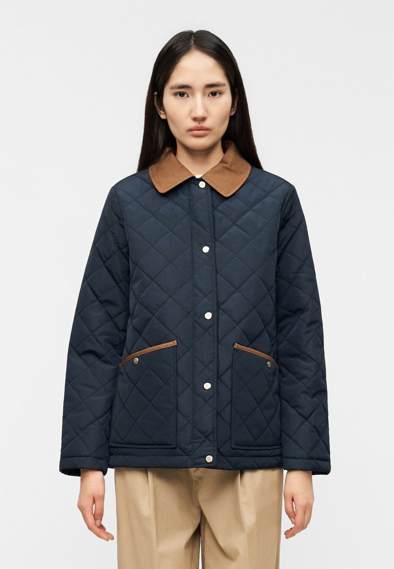 Μπλε ναυτική μπουφάν με ραφές, καφέ γιακά, κουμπιά με κούμπωμα και δύο πλαϊνές τσέπες με δερμάτινες λεπτομέρειες. Ομαλή υφή και άνετη εφαρμογή.