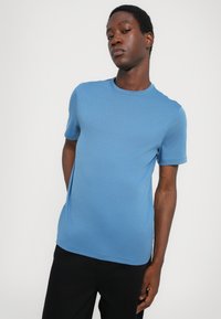 Modra kratka majica s kratkimi rokavi, izdelana iz mehke tkanine, z okroglo ovratnikom in minimalističnim logotipom izvezenim na prsih.