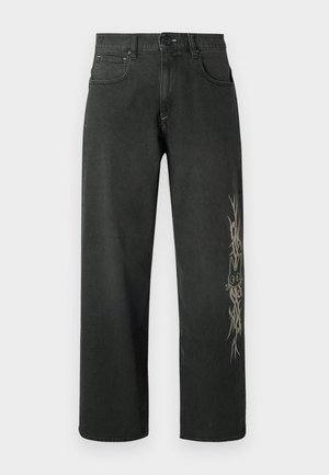 Vaqueros de mezclilla negra de pierna ancha con un diseño gráfico lateral en gris claro. Estilo estándar de cinco bolsillos con cierre de botón y trabillas para cinturón.