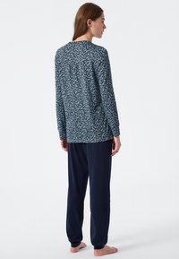 Long-sleeve top in blue with dark pattern, paired with navy pajama pants. Soft fabric, relaxed fit, and elastic waistband on pants.