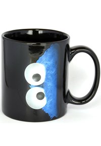 Mug in ceramica nera con due grandi occhi bianchi e un dettaglio in blu peloso. Finitura liscia e lucida con un manico curvo.