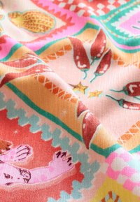 Spalvinga austinė medžiaga su sudėtingais raštais, vaizduojančiais čili pipirus, žvaigždes ir geometrines formas rožinės, oranžinės, žalios ir turkio atspalviais.