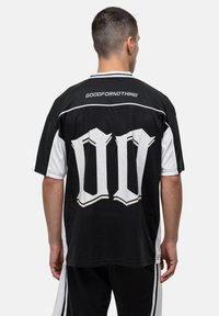 Zwart-wit korte mouwen shirt met gaastextuur, met een grote "00" afbeelding en de tekst "GOODFORNOTHING" op de achterkant.