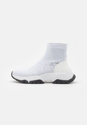 Zapatilla blanca estilo calcetín con parte superior de punto, suela gruesa esculpida, suela negra y logo "GUESS" tejido en el lateral.
