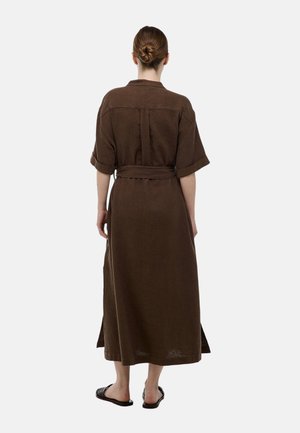 Robe maxi marron à côtes avec manches courtes, taille ceinturée et fente dans le dos ; en tissu texturé, elle arrive aux chevilles.