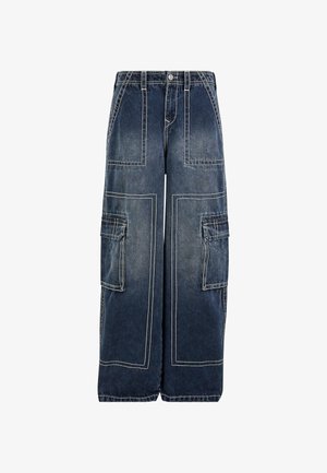 Plati kāju kravas džinsi tumši zilā denima ar kontrastējošiem baltiem šuvumiem. Iespējo divas sānu kravas kabatas un taisnu griezumu.