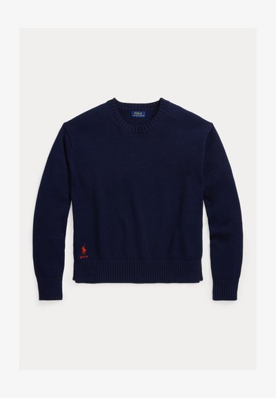 Tumši zils adīts džemperis ar ribotu kakla izgriezumu un apakšu. Apakšējā kreisajā pusē ir izšūta sarkana logo.