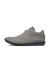 Scarpa casual grigia con punta curva, lacci elastici e suola blu a contrasto. Presenta un logo sul lato esterno.
