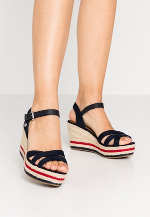 Sandales compensées navy avec base en espadrille tissée, rayures rouge et blanche, bride ajustable à la cheville et lanières croisées sur le dessus.