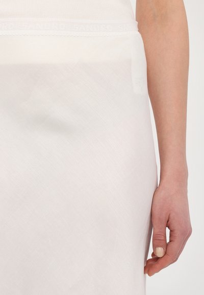 Jupon midi blanc et texturé avec une ceinture à bord festonné arborant un logo en relief. Le matériau est léger et semi-transparent.