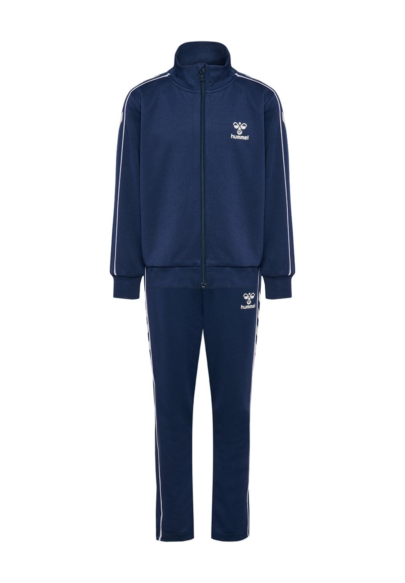 Marinblå träningsoverall tillverkad av mjukt material, med en zip-up jacka med hög krage och matchande byxor. Innehåller vita sidostreifen och logotyp.