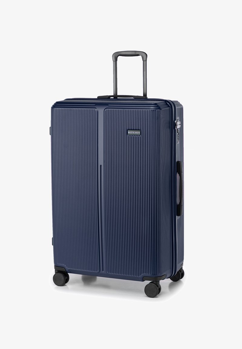 Valigia rigida blu navy con righe verticali, manico telescopico, maniglie di trasporto superiori e laterali, e quattro ruote nere per la mobilità.