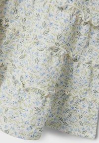 Tissu à motif floral avec des teintes bleu clair et vert, présentant des volants texturés et des détails de couture délicats. Matériau doux et léger.