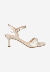Sandales à talons hauts en métal doré avec un bout ouvert, sangle de cheville ajustable et un talon aiguille de 5 cm. Texture lisse, design minimaliste.