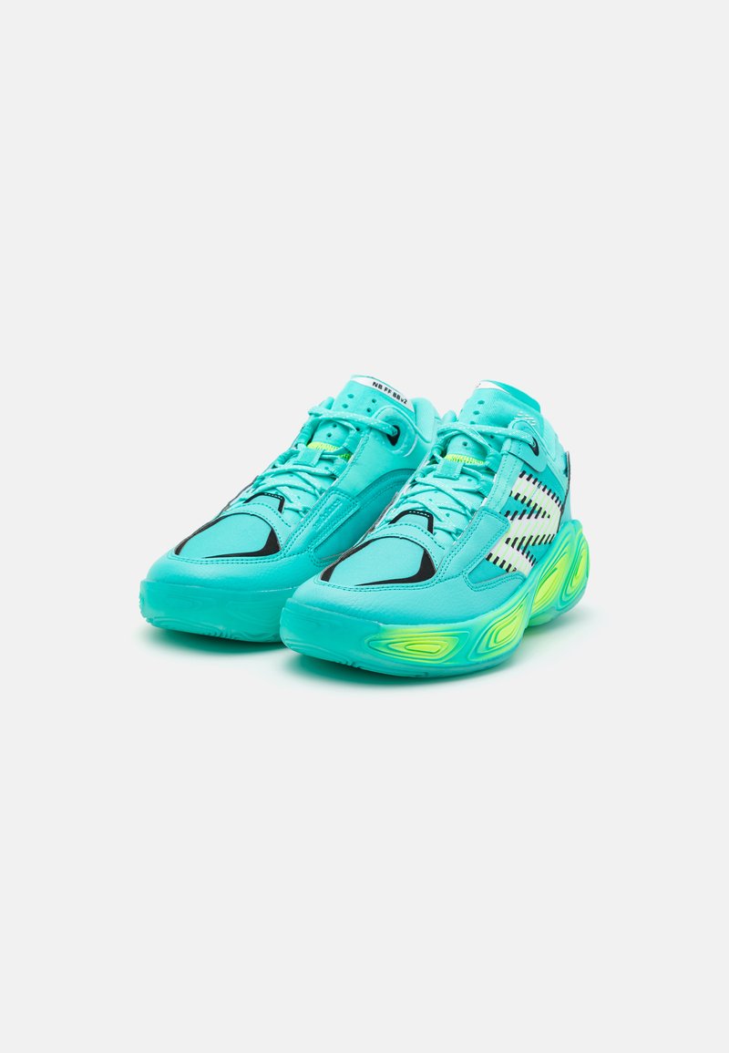Türkise Sportschuhe mit glatter Textur, schwarzen Akzenten und Mesh-Einsätzen; verfügen über eine dicke Sohle mit neon-grünen Elementen.