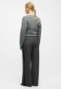 Gray knit sweater with dropped shoulders, paired with wide-leg dark gray pants featuring a drawstring waist and side stripes.
