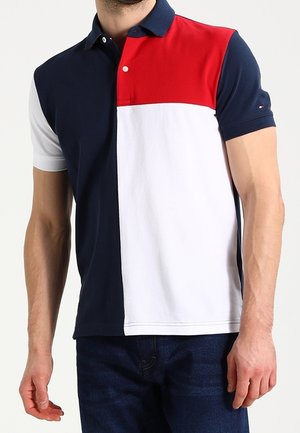 Polo à blocs de couleurs bleu marine, blanc et rouge avec col, boutons et manches courtes ; en coton, avec une texture lisse.
