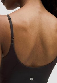 Black athletic top with adjustable straps, smooth texture, featuring a logo at the back. Skin tone and shoulder contours visible.