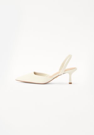 Beige slingback heel with a pointed toe, smooth material, low stiletto heel, and open back design. Minimalist aesthetic with no patterns.