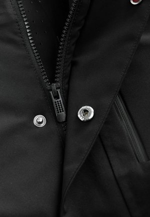 Tessuto di giacca nera con zip, bottone a pressione argento e superficie testurizzata. Presenta una tasca laterale e cuciture dettagliate.