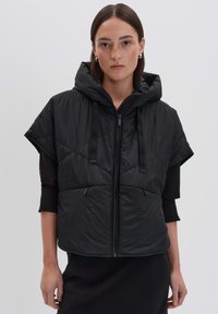 Gilet noir matelassé avec capuche, doté d'une fermeture éclair à l'avant, de manches courtes et de deux poches avant. Tissu texturé avec cordons de serrage ajustables.