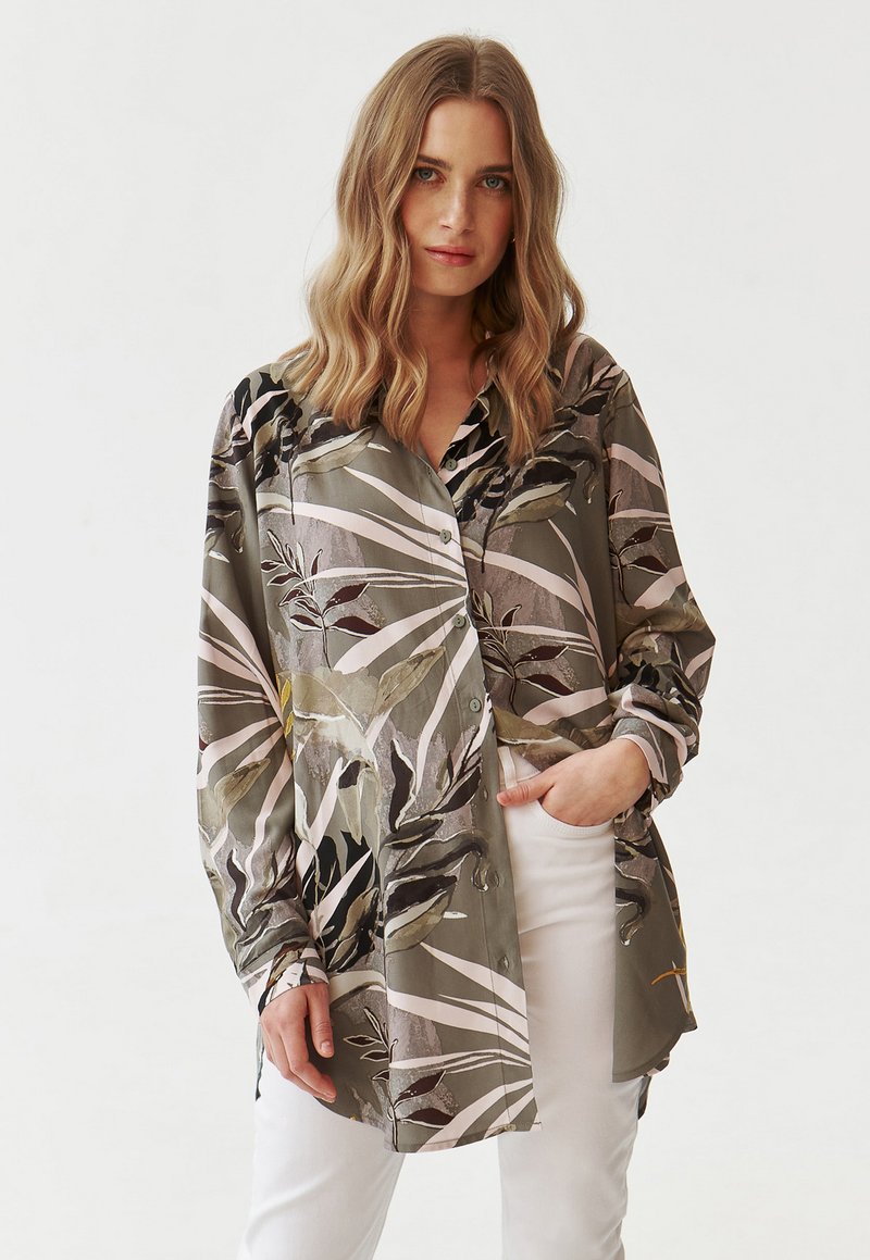 Camicia a maniche lunghe con bottoni di colore verde oliva, decorata con un ampio motivo floreale nei toni del nero, rosa e giallo. Tessuto morbido con una vestibilità rilassata.
