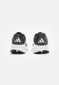 Black and gray athletic shoes with a textured upper, white midsole, and black sole, featuring three white stripes on the heel.