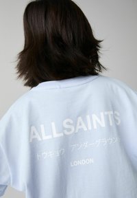 Gaišzilā, liela izmēra džemperis ar baltu tekstu: "ALLSAINTS", japāņu rakstzīmēm un "LONDON" aizmugurē. Mīksta kokvilnas auduma.