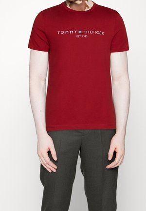 Czerwona koszulka z okrągłym dekoltem, wykonana z bawełny, z logo "TOMMY HILFIGER" i akcentem w postaci flagi. Dopasowany krój, krótkie rękawy i gładka faktura.