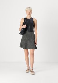 Fekete ujjatlan bodysuit, szürke plissé kötött szoknya, bézs balettcipők bokapánttal és egy fekete táska. Egyszerű, modern dizájn.