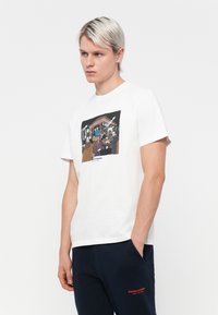 White cotton t-shirt with short sleeves featuring a graphic illustration on the front, depicting various characters in a colorful scene.
