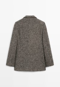 Cappotto a zigzag in grigio e nero, realizzato in lana texturizzata. Caratterizzato da un colletto a scollo a V e maniche lunghe, con una vestibilità su misura.