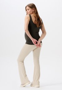 Olijfgroene geribbelde tanktop gecombineerd met beige flared broek. De outfit heeft een getailleerde Silhouet en zachte texturen.