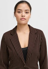 Blazer marrone a righe sottili con rever a punta e chiusura a un bottone, caratterizzato da una texture liscia e strisce bianche a contrasto.