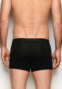 Sorte stribede boxershorts lavet af strækbart stof, med en sort elastik i taljen og lodrette hvide pinstriber på kroppen.