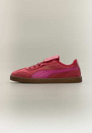 Κόκκινο και ροζ παπούτσι Puma με λαστιχένια σόλα, κορδόνια και μια φλοκάτη πάνω από τη γλώσσα, εμφανιζόμενο από το πλάι σε ανοιχτό φόντο.
