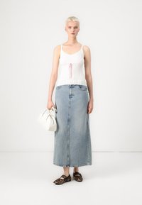 Vit ribbad linne med rosa dragsko, i kombination med en lång ljusblå denimkjol och bruna ballerinas med leopardmönster. Vit handväska som accessoar.