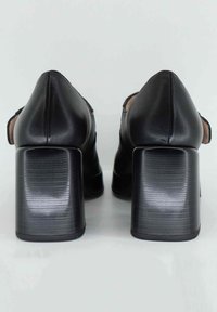 Scarpe nere in pelle con tacco alto, punta affilata e tacco chunky testurizzato. Presentano una finitura liscia e accentuazioni minime.