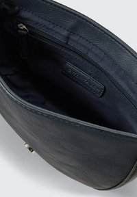 Borsa in pelle di colore blu scuro con una texture liscia, dotata di una tasca con zip e foderata in tessuto. Include un'etichetta del marchio discreta all'interno.